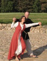 Rotes Schnürkleid aus Leinen mit weißem Unterkleid. Er trägt eine schmale Variante der Rushose mit dunkelblauer Wolltunika im Slawischen- oder Wikinger-Stil.